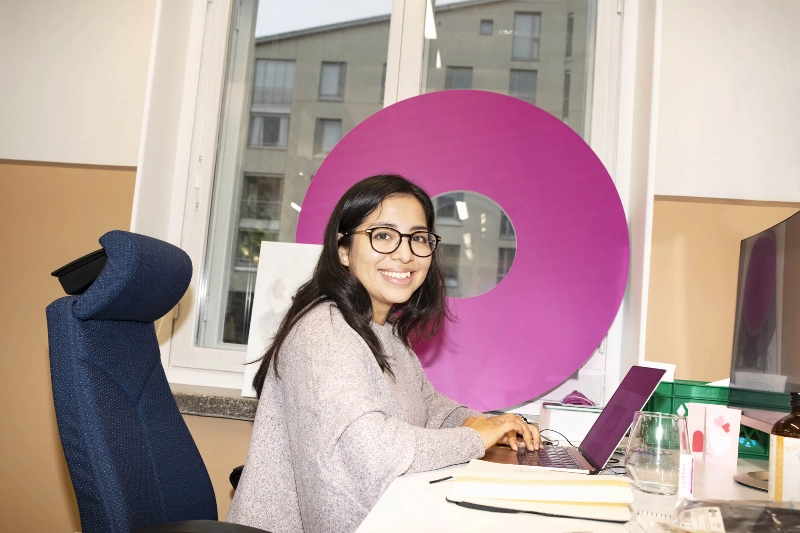 A woman smiles at the camera while working in her office. - N2 Albiino / Helsinki Partners A woman smiles at the camera while working in her office. - N2 Albiino / Helsinki Partners