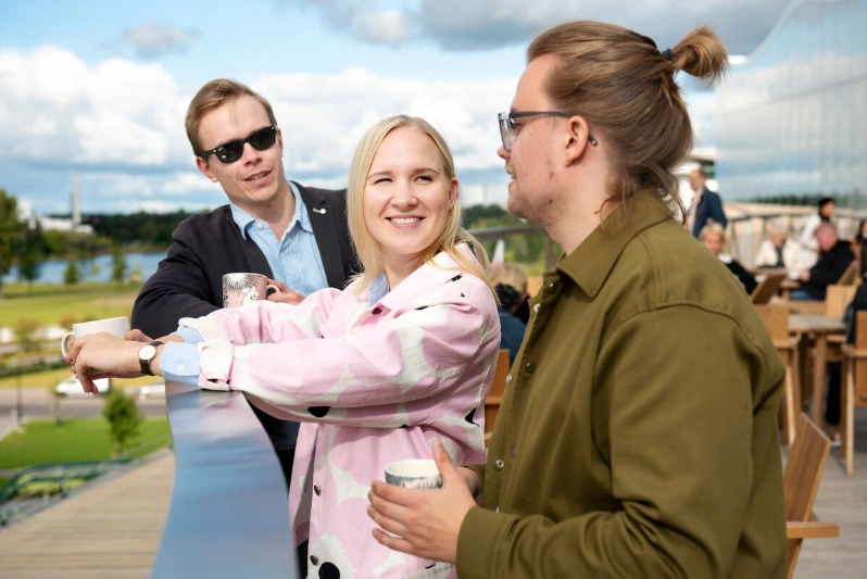 Three colleagues enjoy coffee on an outdoor terrace. - Markus Sommers / Business Finland Three colleagues enjoy coffee on an outdoor terrace. - Markus Sommers / Business Finland